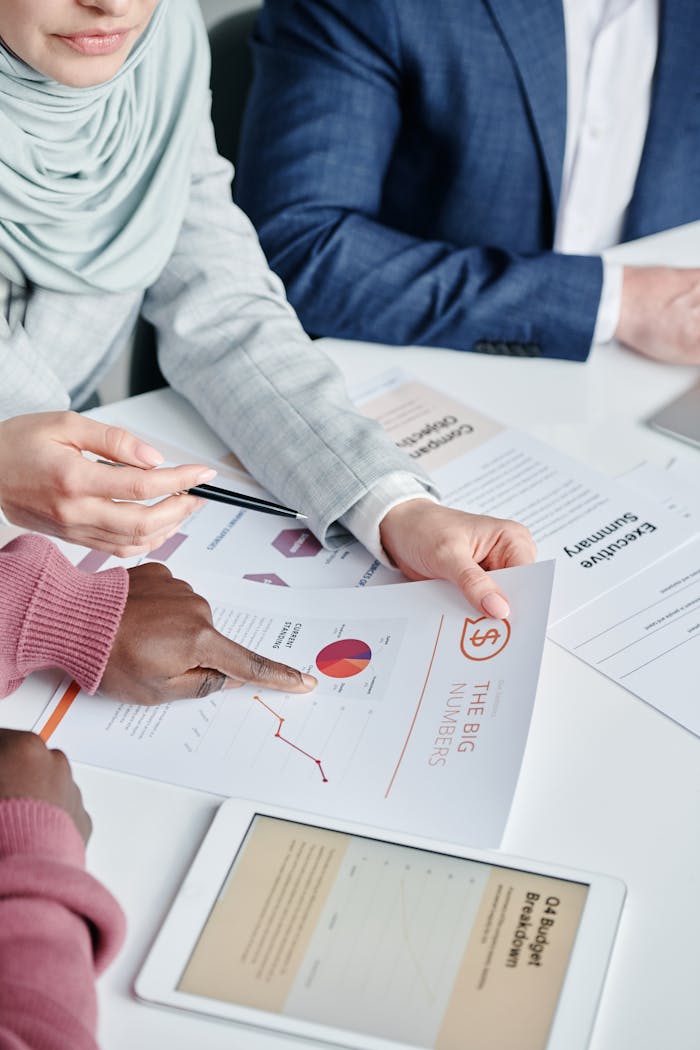 Diverse team members collaboratively reviewing business charts and documents during a meeting indoors.